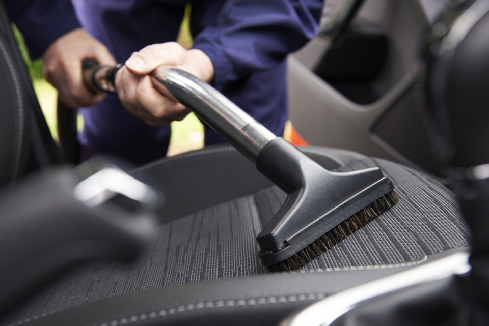 Man vacuuming interior of his car