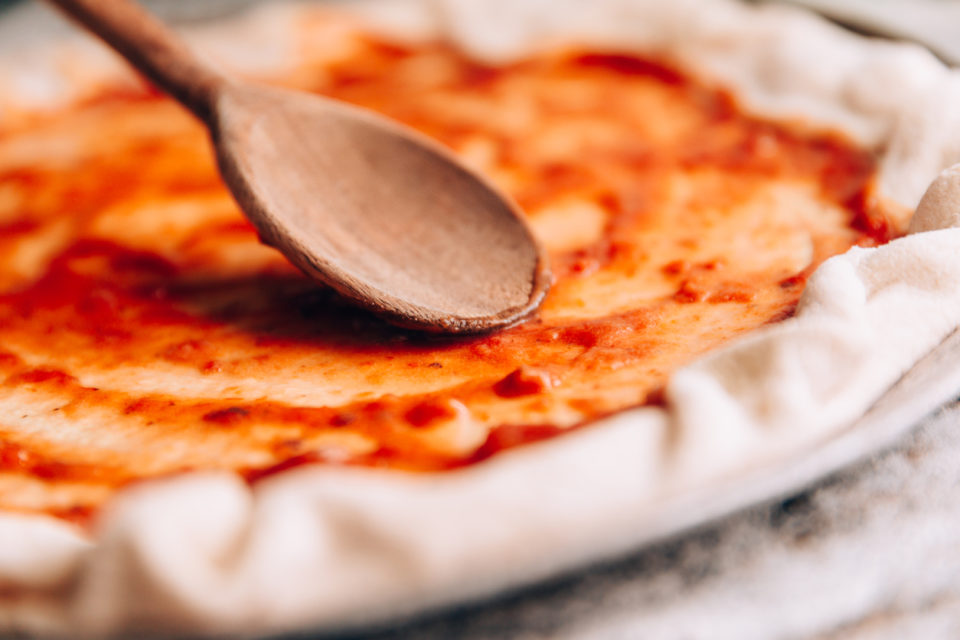 Spreading tomato sauce on pizza pan