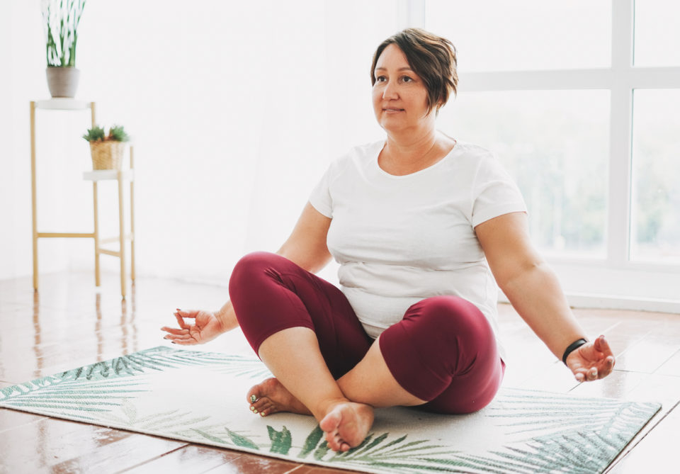 Adult woman practicing yoga at bright studio