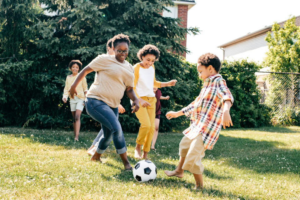 Family playing soccer in backyard