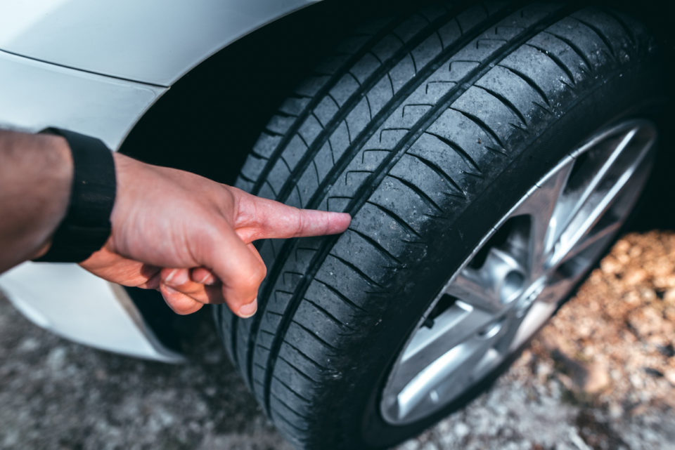 A human hand checking a tire tread