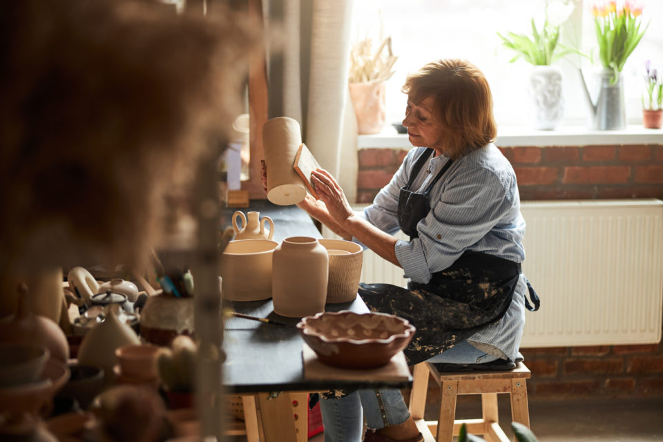 Charming female potter polishing earthenware in workshop