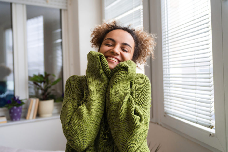 young woman smiling while wearing cozy green sweater