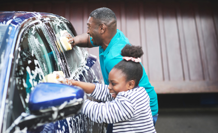 Shot of a father and his daughter washing their car outside