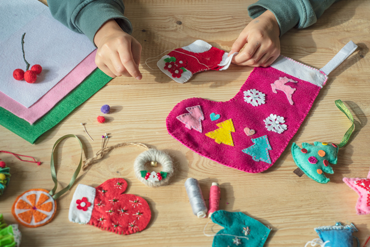 Hands holding needle and sewing felt christmas sock for Christmas and new year decor