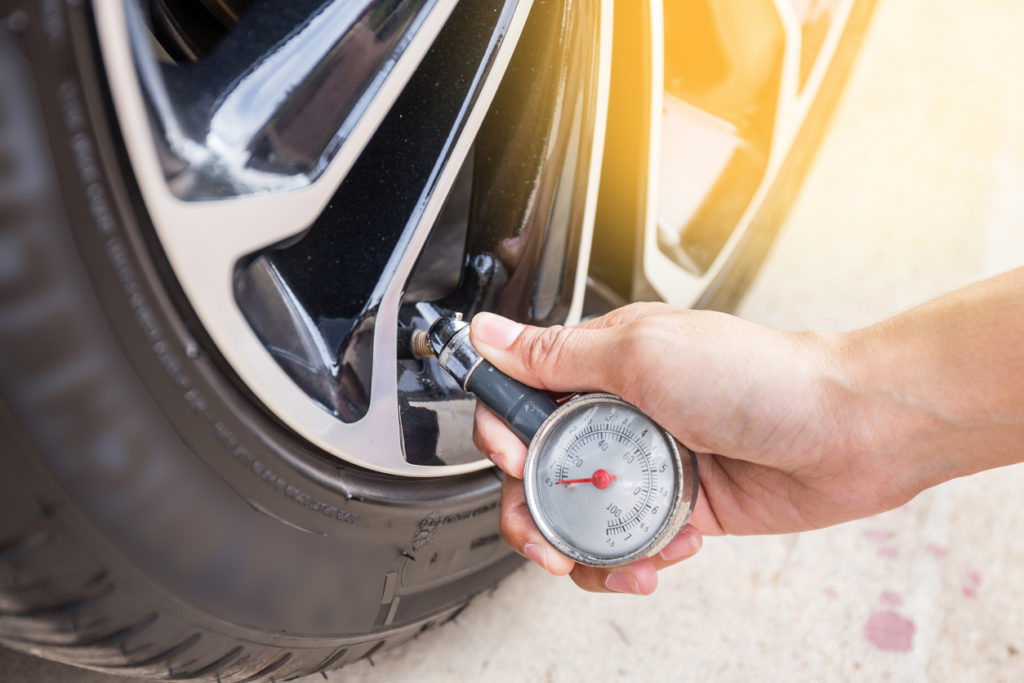 Close-up of hand holding pressure gauge for car tire pressure measurement