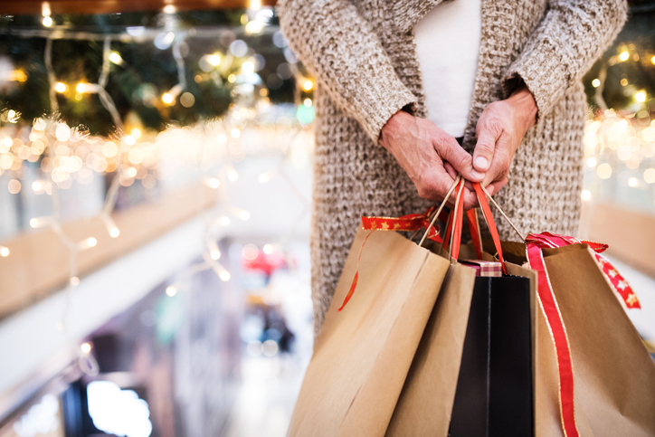 Unrecognizable senior woman with paper bags doing Christmas shopping. Shopping center at Christmas time.