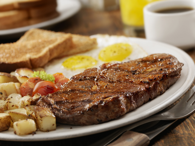 Grilled Rib Eye Steak with Sunny-side up Eggs, Hash Browns, Grilled Tomatoes and Toast